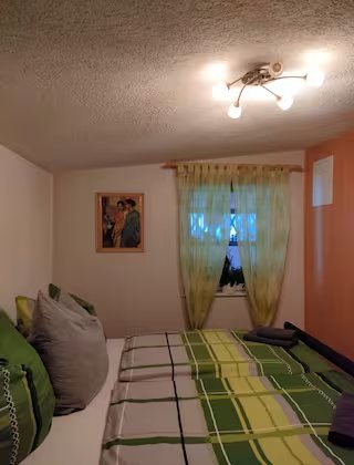 Wohnung 1: Zweites Schlafzimmer mit grüner Tagesdecke