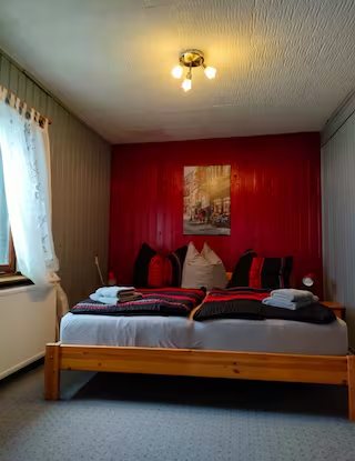 Wohnung 1: Schlafzimmer mit roter Wand und Holzbett