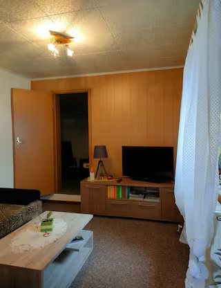 Wohnung 1: Wohnbereich mit Fernseher und Sideboard